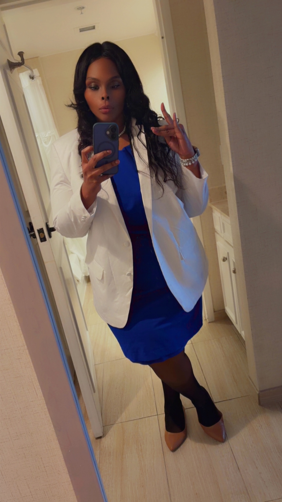 Latoya Jeeter taking a mirror selfie in a white blazer over a royal blue dress, wearing pearls